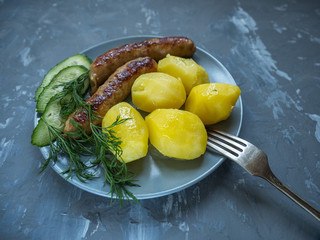 boiled young potatoes with grilled sausages slices of cucumber