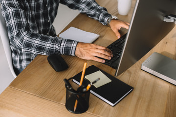 cropped shot of man in plaid shirt using computer at workplace © LIGHTFIELD STUDIOS