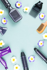 Hairdressing tools with flowers on blue wooden background