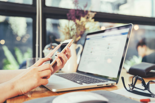 Young woman hands holding using smartphone and laptop computer working and business contact in coffee shop