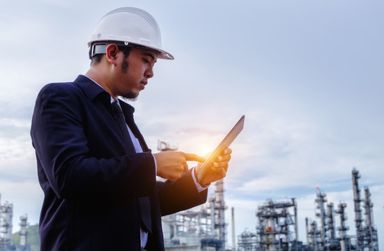 The engineer is working with tabet with large industry background.