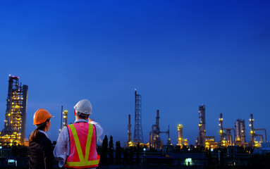The engineers are standing on large industry background.