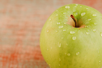 Green apple with water drops isolated on wooden background