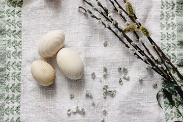 simple wooden easter eggs and willow buds and wax sticks on rustic napkin with embroidery