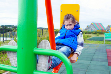 Fototapeta na wymiar White little girl wearing blue jeans and sleeveless jacket on a sports ground outdoor