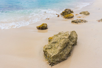 A beautiful sandy beach with large rocks and waves.