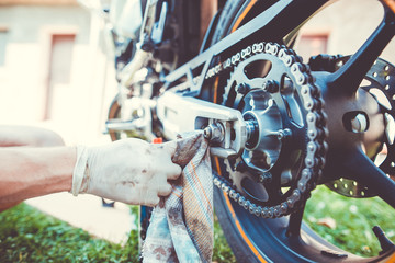 Man hands cleaning motorbike doing maintenance by rag and by detergent - obrazy, fototapety, plakaty