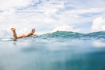 Beautiful young surfer girl in sexy pink bikini paddle surfing longboard on big waves in open ocean. Modern family lifestyle, people water sport adventure camp and extreme swim on summer vacation.