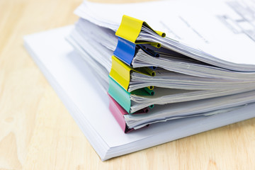 Color paper clip with Stack of papers documents on wood table in office 