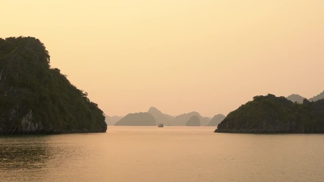 Cruise Boat in Ha Long Bay at Sunset in the limestone islands of Cat Ba National Park, North East Vietnam