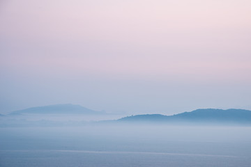 Mountain and sea covered with morning mist before sunrise.