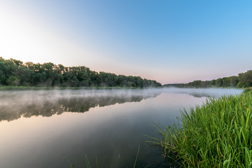 Fototapeta na wymiar sunrise on the river. fog on the river. panoramic view, trees reflected in the water