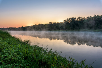 Fototapeta na wymiar sunrise on the river, the red sky before sunrise. fog on the river