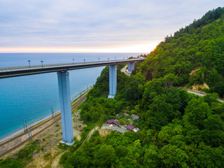 Drone view of the Zubova Schel viaduct and mountainside with forest on the background of the sea in overcast summer day, Sochi, Russia
