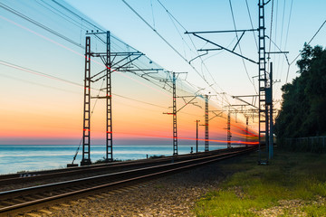 Beautiful landscape of a railroad with motion blurred train on the background of the sea at twilight, Sochi, Russia
