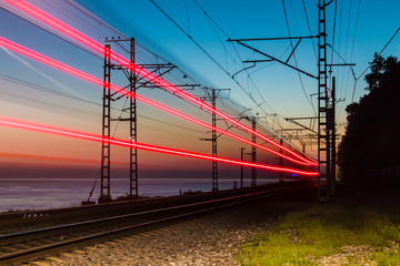 Beautiful landscape of a railroad with motion blurred train on the background of the sea at twilight, Sochi, Russia
