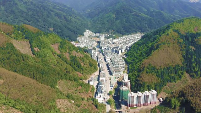 Drone aerial shot of mountain valley city Huangshan city in Tunxi, Anhui. Huangshan mountain tourist attraction, with quaint modern village between giant mountains during very hot summer in China.