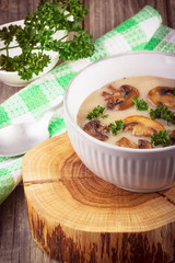 Mushroom cream soup in ceramic bowl on rustic wooden background