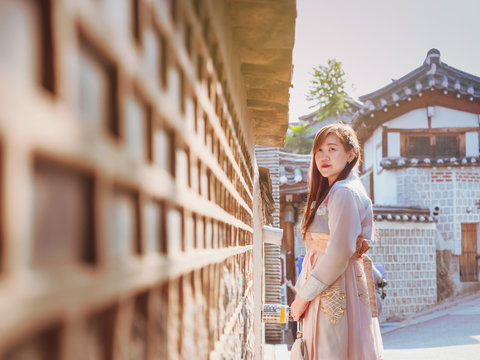 travel and tourist asia concept from beautiful woman in korea traditional cloth (hanbok) relax, take picture in vintage town with rim light and soft focus background
