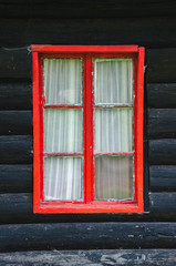 Red rustic window on a black wooden wall