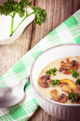 Mushroom cream soup in ceramic bowl on rustic wooden background