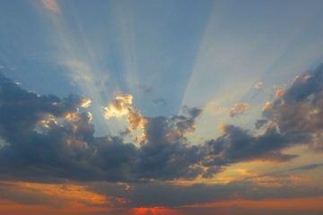 Sun rays shining through dark clouds at sunset, natural background 