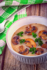 Mushroom cream soup in ceramic bowl on rustic wooden background