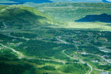 A summer landscape of a village and mountains from a birds eye view.