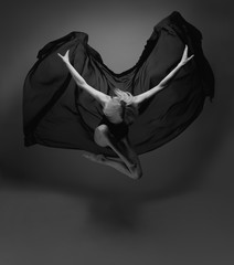 A girl in a jump with a flying black cloth