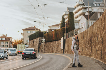 Outdoor portrait of young woman posing on the city street, wearing silver jacket