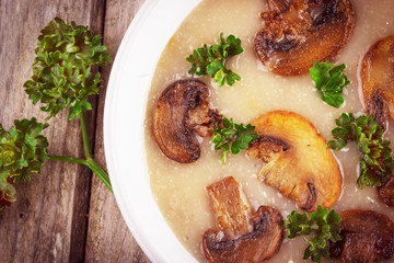 Mushroom cream soup in ceramic bowl on rustic wooden background