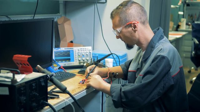 Worker with prosthetic hands brazing a circuit in a workshop