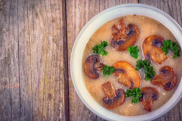 Mushroom cream soup in ceramic bowl on rustic wooden background