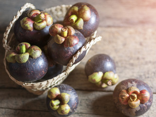 Mangosteen is placed in a basket on a wooden table.