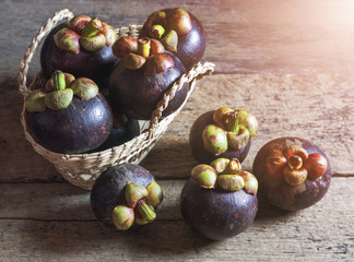 Mangosteen is placed in a basket on a wooden table.