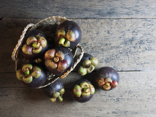 Mangosteen is placed in a basket on a wooden table.