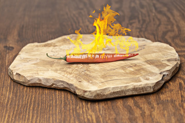 Feuriger Orangefarbener Peperoni auf einem Holzbrett