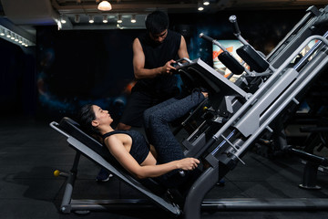 Fototapeta na wymiar Fit woman working out with trainer at the gym, Woman doing muscle training at the gym. Athlete working out at the gym by pulling weight.