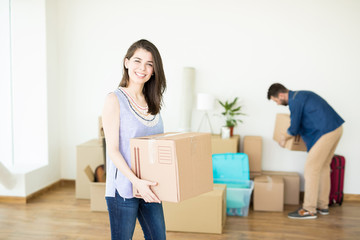 Fototapeta na wymiar Female Owner Smiling And Carrying Box In New House
