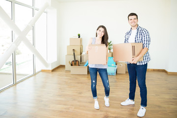 Fototapeta na wymiar Couple Carrying Moving Cardboard Boxes In New Luxury Home