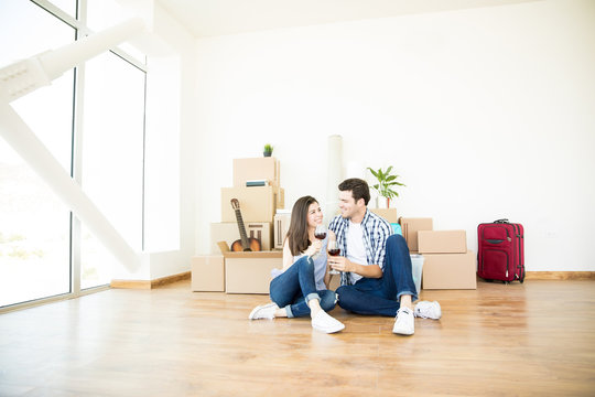 Man And Woman Holding Wineglasses Against Boxes In New Home