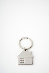 Key and keychain in the shape of a house isolated on white background.