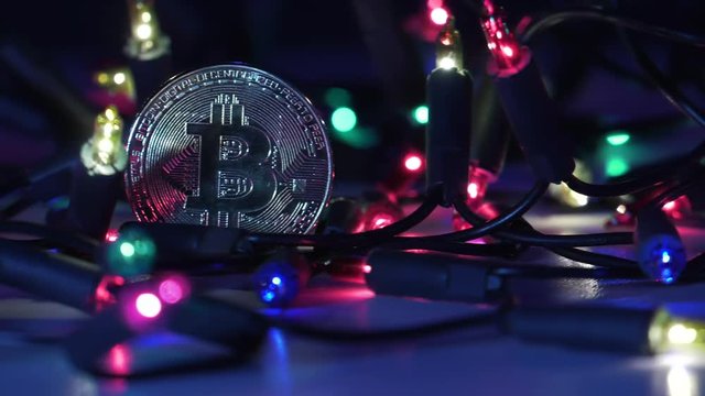 Physical golden Bitcoin. Festive atmosphere. Colorful Christmas tree lights in the background. BTC is a cryptocurrency and is the first decentralized peer-to-peer payment network.