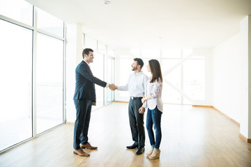 Agent Shaking Hands With Man By Woman In New Home