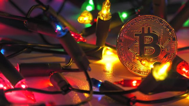 Physical golden Bitcoin. Festive atmosphere. Colorful Christmas tree lights in the background. BTC is a cryptocurrency and is the first decentralized peer-to-peer payment network.
