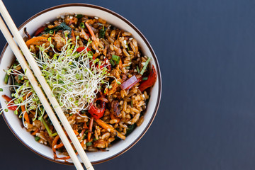 Plate of wok vegetable rice with microgreen on the dark background