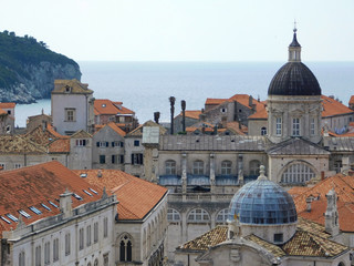 Obraz premium View of Dubrovnik, historic Old Town with buildings and red roofs on the background of the sea, sky, nearby island, Croatia