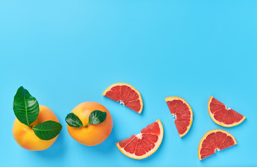 Two grapefruit with  green leaf and grapefruit slices on a blue background