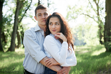 Naklejka premium young couple walking in the forest, summer nature, bright sunlight, shadows and green leaves, romantic feelings