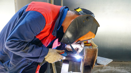 The professional welder works with argon-arc welding. Welds a pipe with a pipe DN50. Butt weld..
